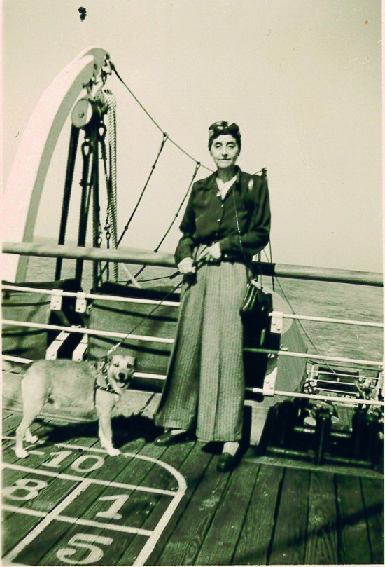 Kvinne med hund i bånd stående på et skipsdekk