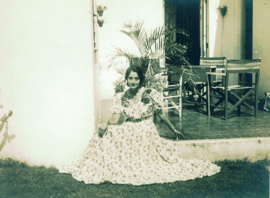 Kvinne i sid kjole sittende på en terrasse