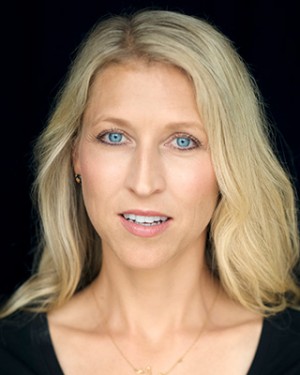 Kvinne med blond hår og blå øyne mot sort bakgrunn