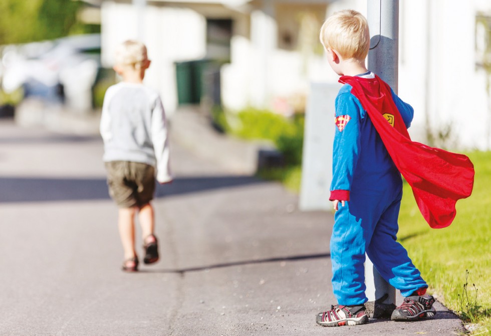 Gutt i Supermann-kostyme som ser etter en annen gutt som går sin vei