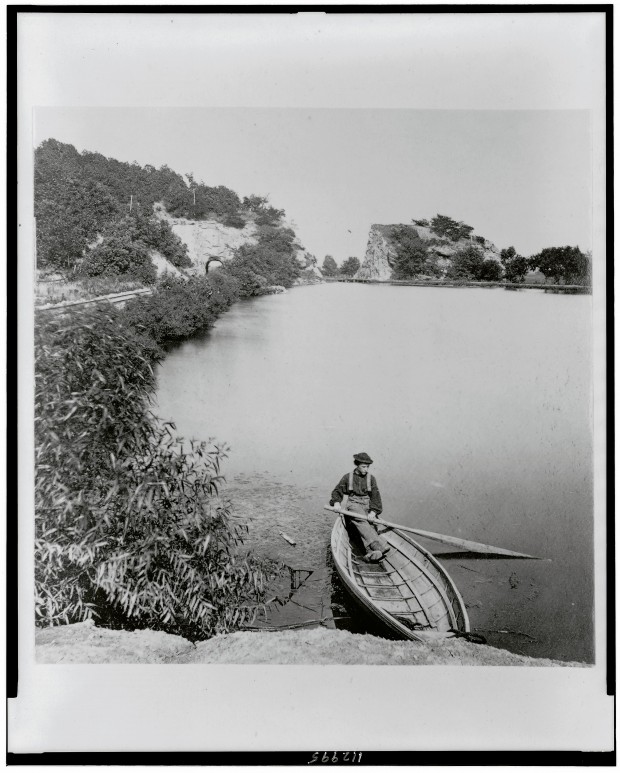 Svarthvitt fotografi av landskap og vann med mann i båt